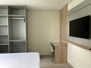 een slaapkamer met een bed, een bureau en een televisie bij Loft Solaris Apart Hotel - Suíte - Apt. N.106 in João Câmara