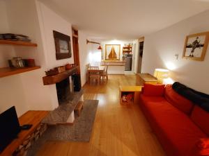 uma sala de estar com um sofá vermelho e uma lareira em La MaisonB - Arly em La Thuile
