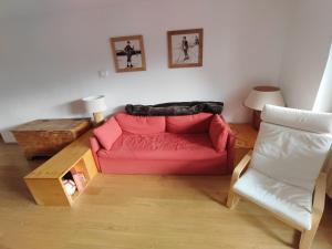 uma sala de estar com um sofá vermelho e uma cadeira em La MaisonB - Arly em La Thuile