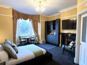 a bedroom with a bed and a table and a television at Melbury Rooms & Studios in Exeter