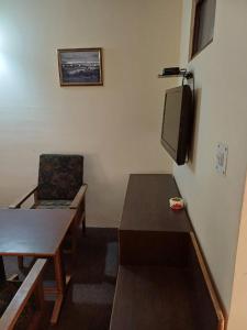 a room with a table and a tv and a chair at Hotel Town Centre , Srinagar in Srinagar