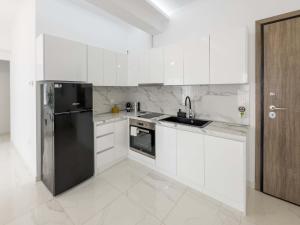 a kitchen with white cabinets and a black refrigerator at Arcade Apartments in Volos
