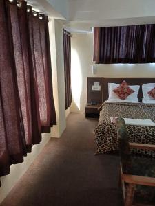 a bedroom with a bed and a couch and curtains at Hotel Town Centre , Srinagar in Srinagar