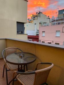 una mesa y sillas en un balcón con puesta de sol en MT Nuevos Apartamentos y Suites con baño privado, en Mataró