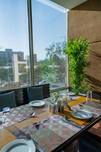 a dining table with a view of a large window at Royal Orchid Central Jaipur, Bani Park in Jaipur