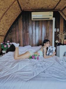 una mujer acostada en una cama leyendo un libro en The sun Sky monjam เดอะซัน สกาย ม่อนแจ่ม en Mon Jam