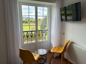 Habitación con 2 sillas y ventana en Luarca Zabala Hotel en Luarca