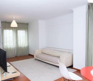 uma sala de estar com um sofá branco e uma televisão em Paulo Guest Apartment nas Caldas da Rainha