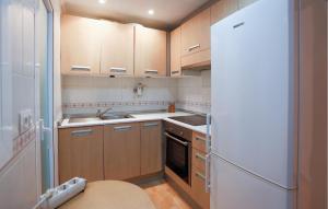 a kitchen with wooden cabinets and a white refrigerator at Cozy Apartment In Torrevieja With Wifi in Torrevieja