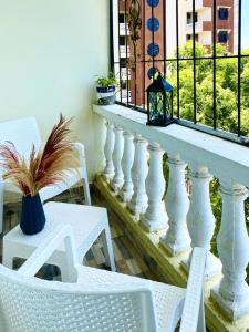 d'un balcon avec des chaises blanches, une table et une fenêtre. dans l'établissement Unique apartment 2, à Mombasa