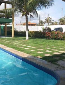 a swimming pool with a palm tree in a yard at Casa de Praia na Tabuba-Ceará in Caucaia