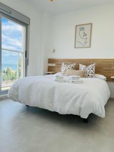 a bedroom with a white bed with a large window at Apto. Burbujas - Marenia´s Dream in Denia