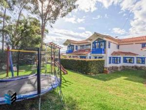 a playground in a yard in front of a house at HOTEL & CABAÑAS CASHILUNA in Villa de Leyva