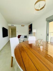 a dining room with a wooden table and white chairs at Apto. Burbujas - Marenia´s Dream in Denia