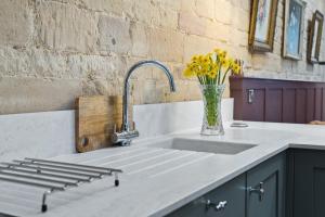 - un évier de cuisine avec un vase de fleurs jaunes dans l'établissement Copper Beech Cottage, à Oakham 10 autres photos
