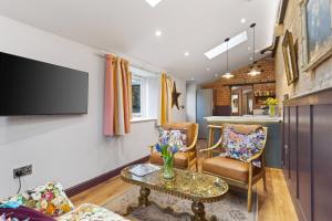 un salon avec deux chaises et une télévision dans l'établissement Copper Beech Cottage, à Oakham