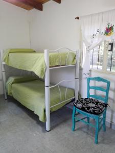 a bedroom with two bunk beds and a blue chair at Cabaña el rincón de Termas in Termas de Río Hondo