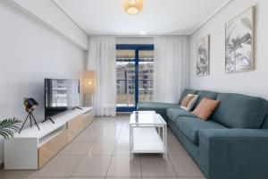 a living room with a blue couch and a tv at ApartUP Patacona Infinity in Valencia