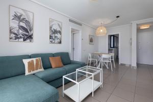 a living room with a blue couch and a table at ApartUP Patacona Infinity in Valencia +46 photos