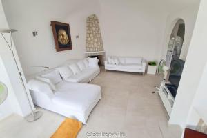 een woonkamer met witte banken en een open haard bij BeHappyVilla in Benissa