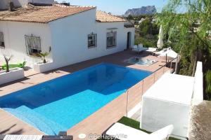 een villa met een zwembad en een huis bij BeHappyVilla in Benissa