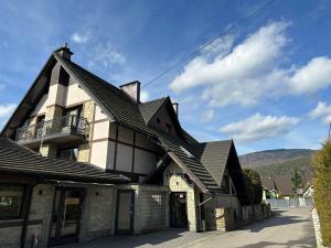 a house with a gambrel roof with a balcony at Pensjonat Melaxa in Węgierska Górka