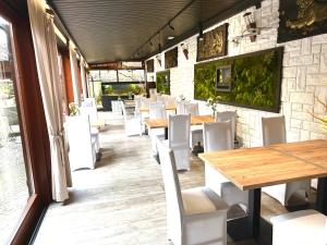 un restaurante con mesas de madera y sillas blancas en Pensjonat Melaxa en Węgierska Górka