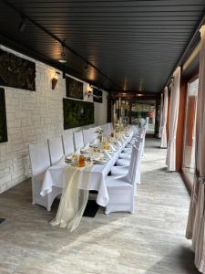 una mesa larga con mesas blancas y sillas blancas en Pensjonat Melaxa en Węgierska Górka