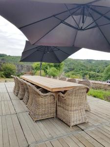 a wooden table with wicker chairs and an umbrella at Le Repos du Clocher in Daverdisse