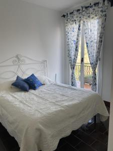 uma cama com almofadas azuis num quarto com uma janela em Casa Panorama em Leivi