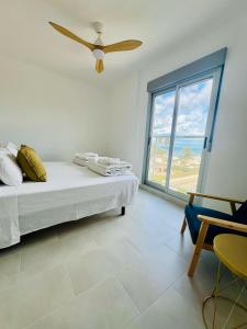 a bedroom with a bed with a ceiling fan and a window at Àtico Espuma - Marenia´s Dream in Denia