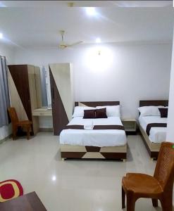 a hotel room with two beds and a chair at Tharavad Residency in Iritti