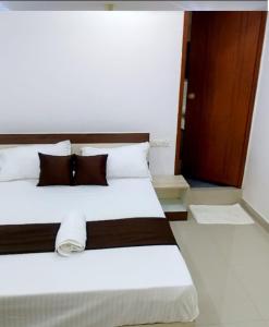 a bedroom with a bed with white sheets and brown pillows at Tharavad Residency in Iritti