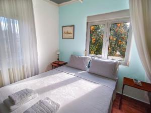 a bedroom with a large white bed with two windows at Calda Ospitalita in Néa Karyá