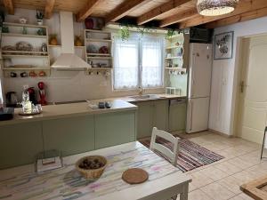 cocina con armarios verdes, mesa y fregadero en Dafne Holiday House, en Koxaré