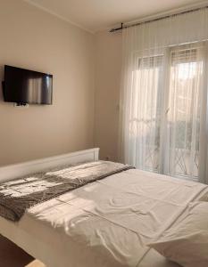 um quarto branco com uma cama e uma janela em M&N Residence Tivat em Tivat