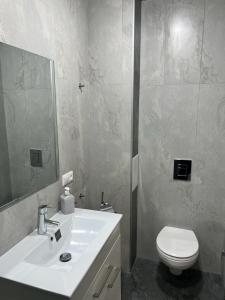 La salle de bains est pourvue d'un lavabo blanc et de toilettes. dans l'établissement Modern Apartment, à Erevan