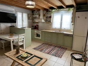 cocina con armarios verdes, mesa y comedor en Dafne Holiday House, en Koxaré