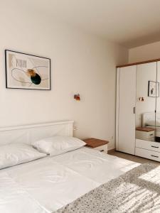 a white bedroom with a large white bed and a cabinet at M&N Residence Tivat in Tivat