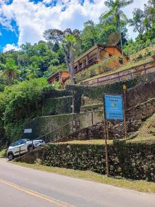 un panneau sur le côté d'une colline avec une maison dans l'établissement Casa Fofa! No Coração de Araras!, à Petrópolis