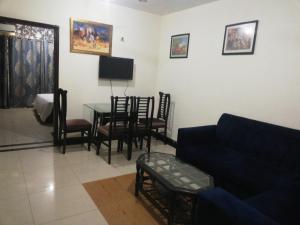 uma sala de estar com um sofá, uma mesa e cadeiras em Two Bedrooms Apartment Near DHA & Airport em Lahore