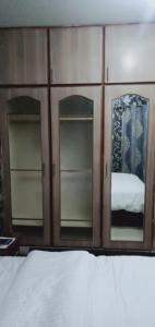 a wooden cabinet with two mirrors and a bed at Two Bedrooms Apartment Near DHA & Airport in Lahore