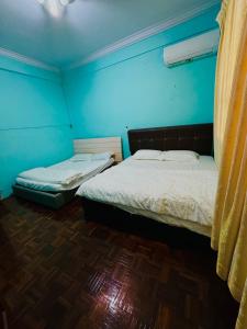 2 Betten in einem Zimmer mit blauen Wänden und Holzböden in der Unterkunft HM AIRBNB in Sibu