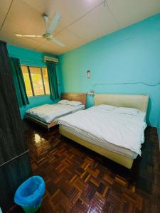 two beds in a room with blue walls at HM AIRBNB in Sibu