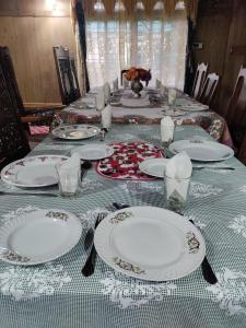 una mesa larga con platos blancos y servilletas. en Queens Lakehouse en Srinagar