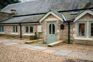 une petite maison en pierre avec une porte verte dans l'établissement Copper Beech Cottage, à Oakham