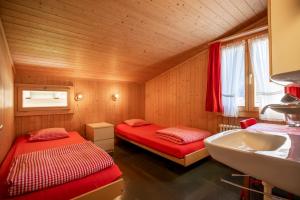 a small room with two beds and a sink at Simons Herberge in Meiringen