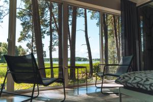 1 dormitorio con vistas al lago y 2 sillas en BOSE and Bang&Olufsen lofts on a lake by Gauja Club, en Gauja