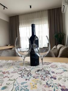 two wine glasses sitting on a table with a bottle of wine at Apartment ALPHA in Banja Luka