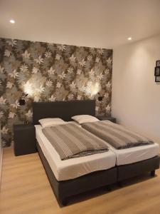a large bed in a bedroom with a wall at DE LANDSHOEVE vakantiewoningen in Zwalm